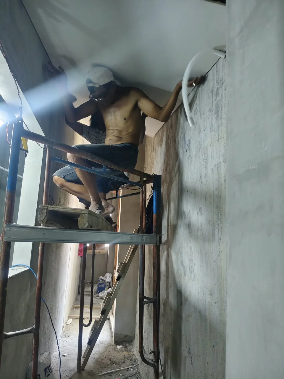 Pekerja berada di atas perancah saat pengerjaan area plafon interior bangunan